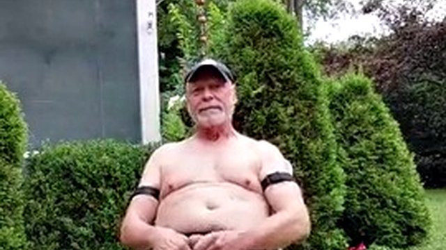 Gardener dad working in the garden and hosing
